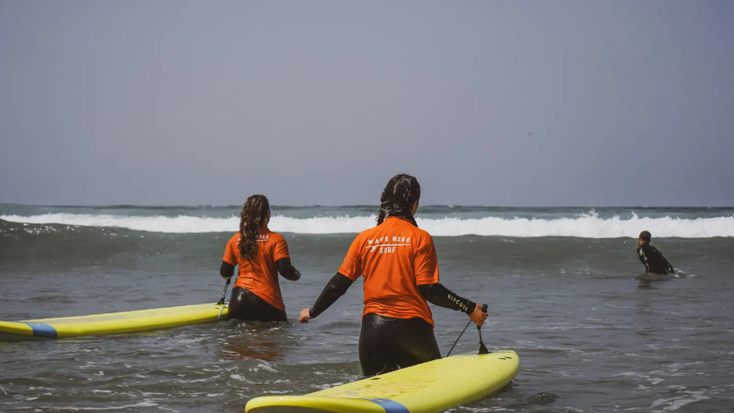Un istruttore accompagna un giovane surfista nella schiuma ad Agadir